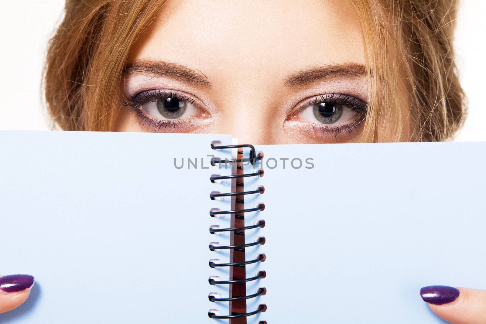 Lovely girl hiding behind notebook, white background