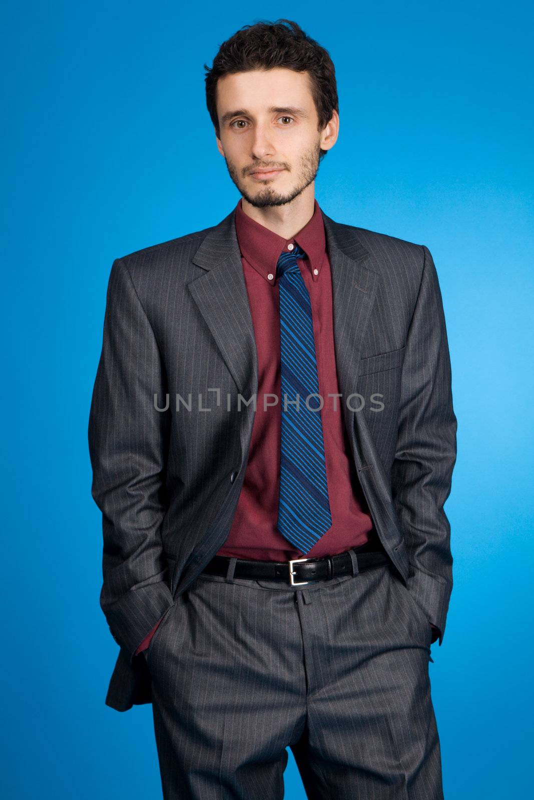 Young handsome businessman studio portrait, blue background