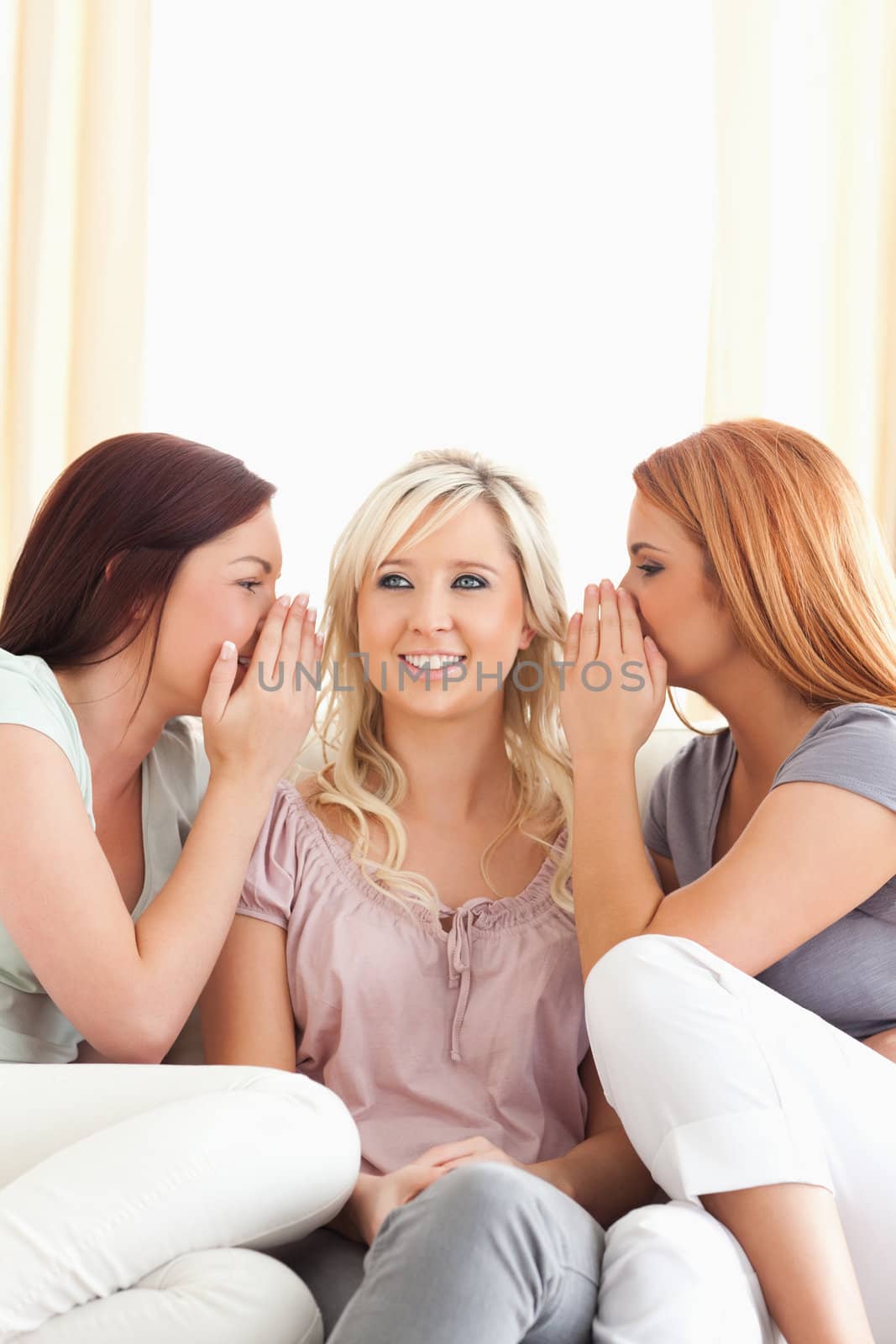 Cute woman being told two secrets at a time in a living room