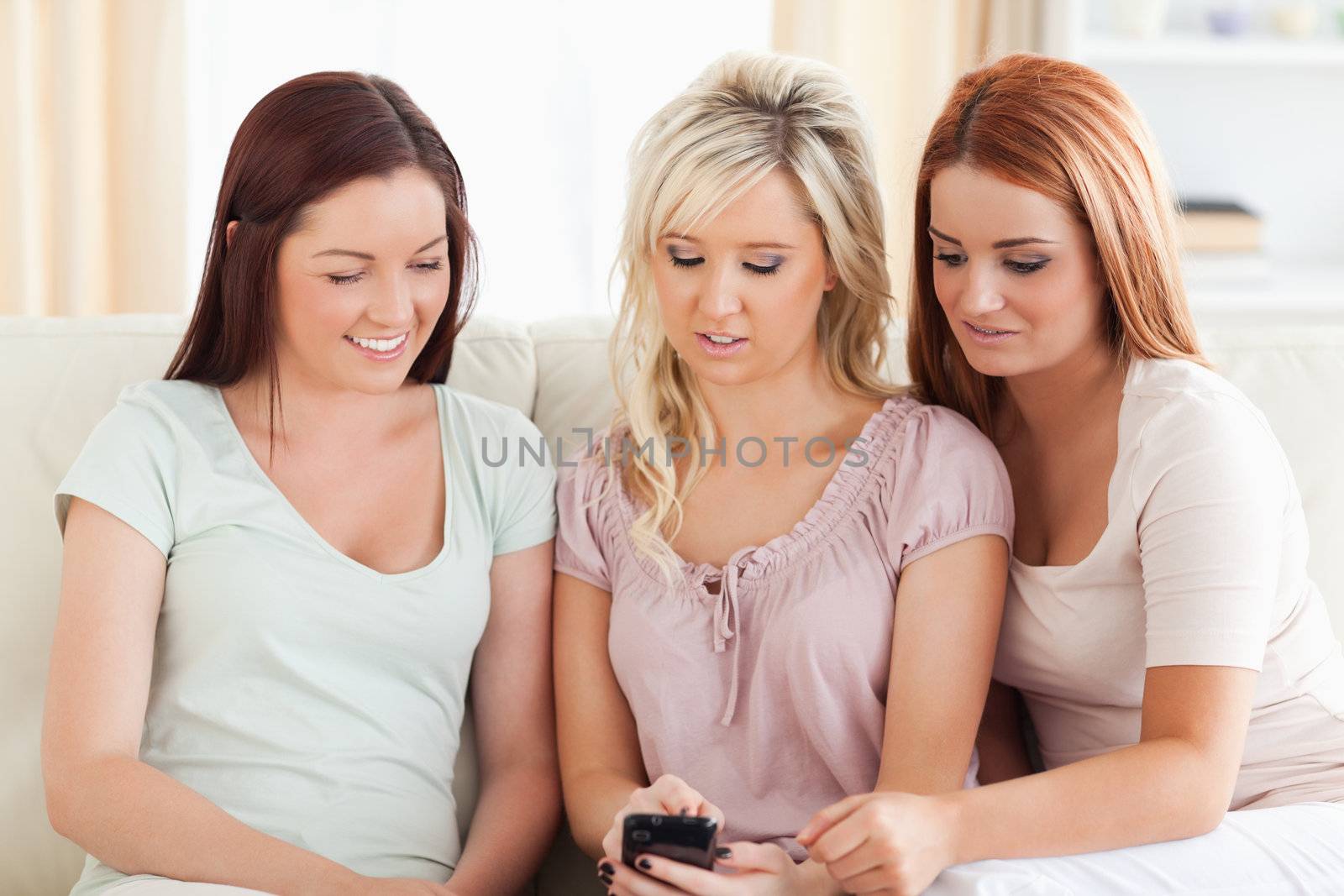 Young women lounging on a couch with a phone in a living room