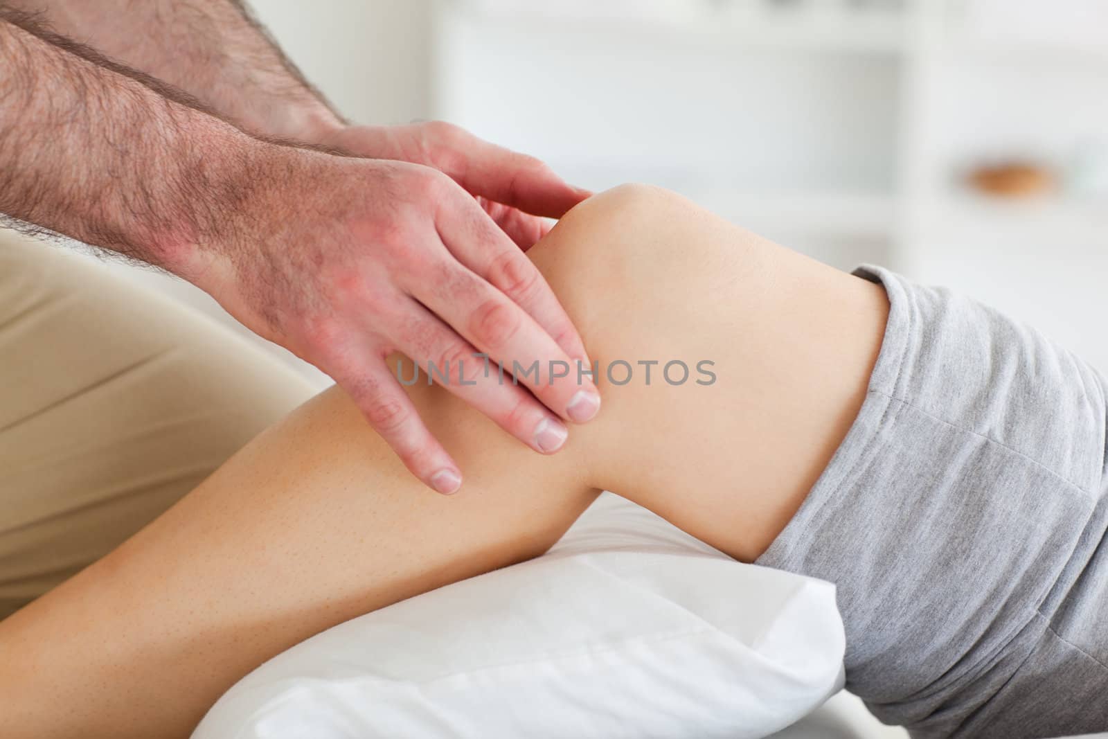 Man massaging a lying woman's knee in a room
