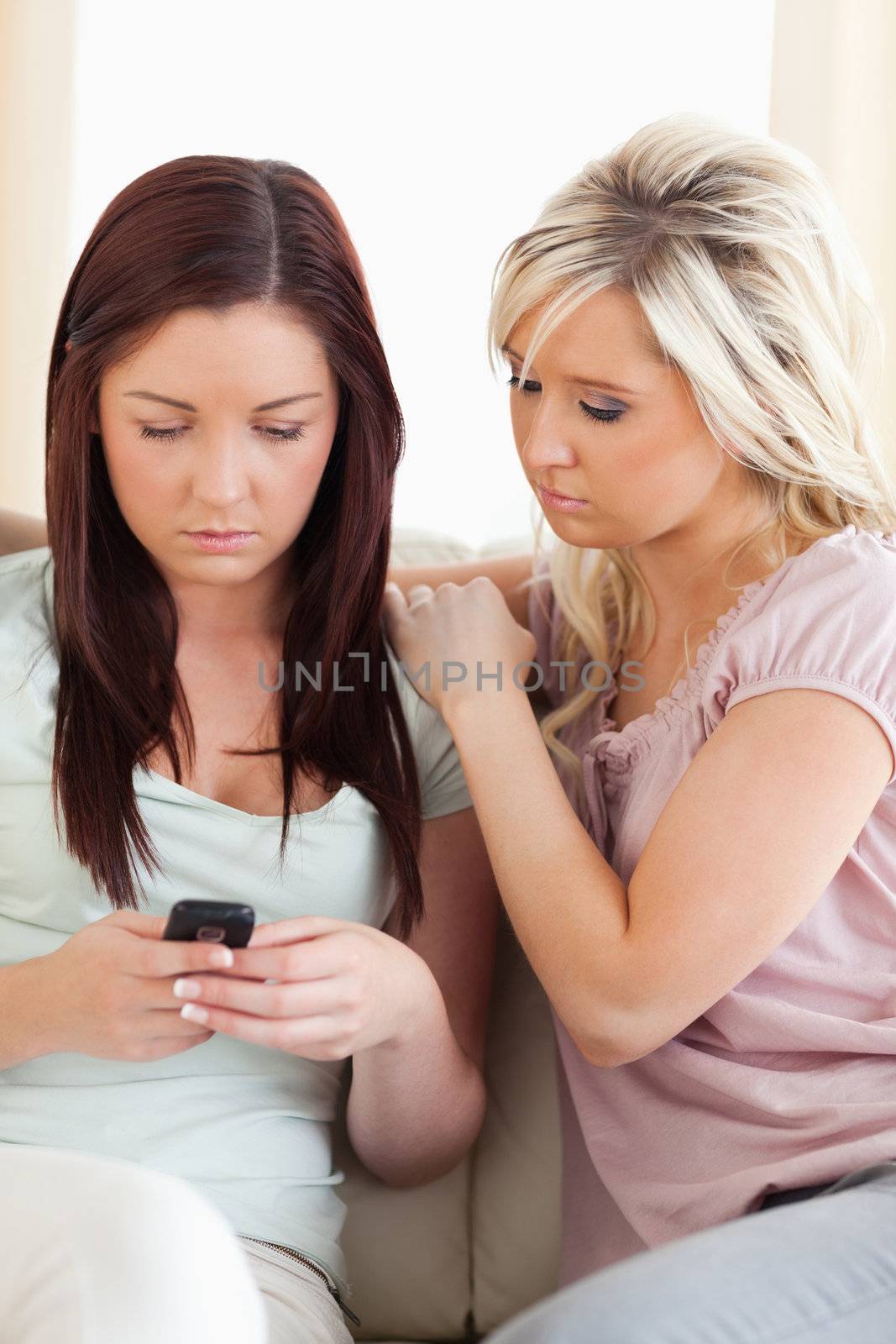 Shocked Women sitting on a sofa with a phone by Wavebreakmedia