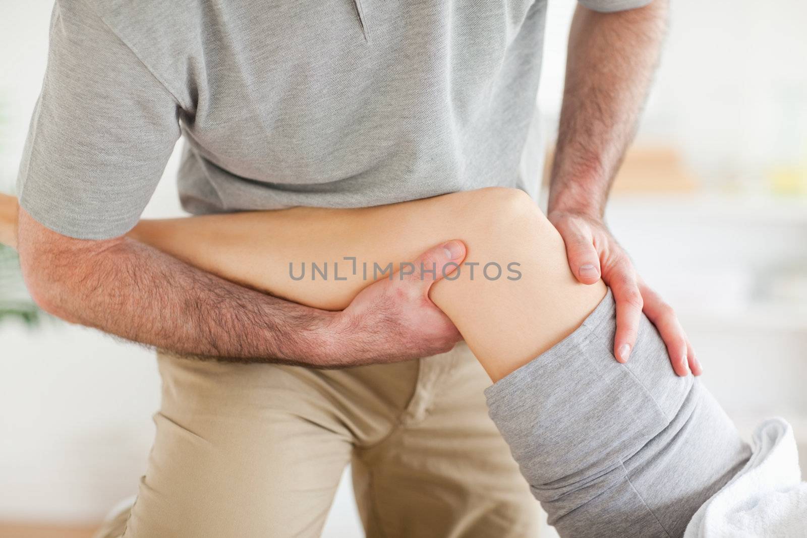 Chiropractor massaging a woman's knee in a room