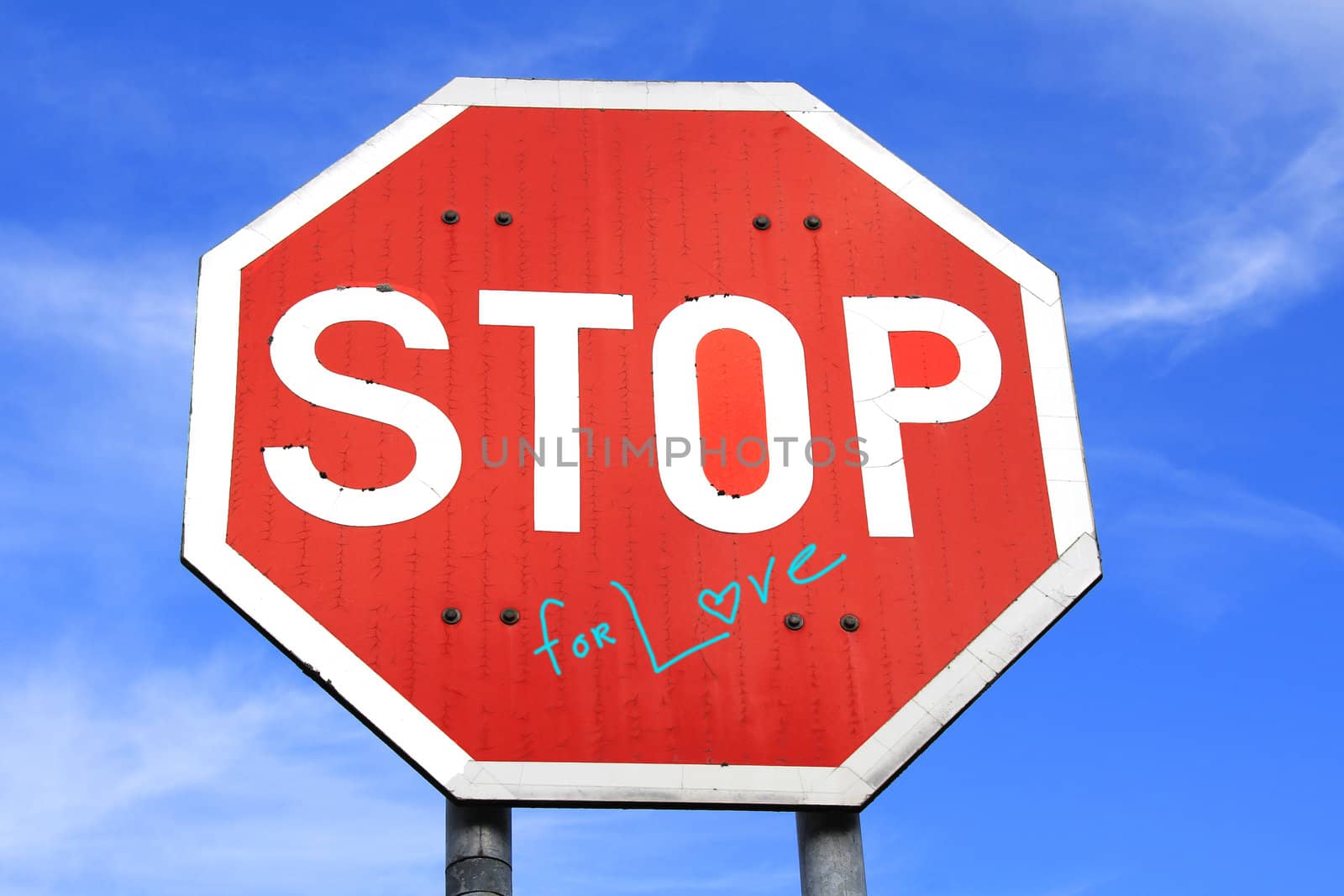 Stop For Love traffic sign against blue sky with some clouds. Text design added by photographer in post production.