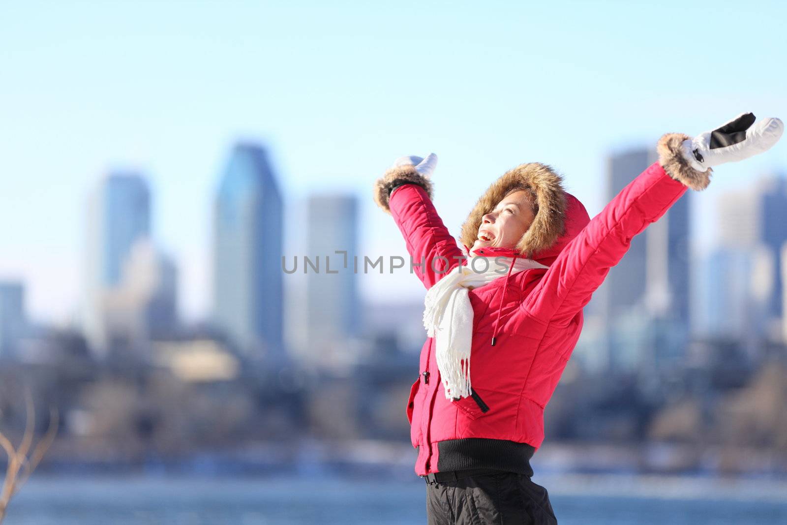 City winter woman happy standing excited and elated with arms raised in joy. Beautiful young woman and Montreal City skyline, Quebec, Canada.