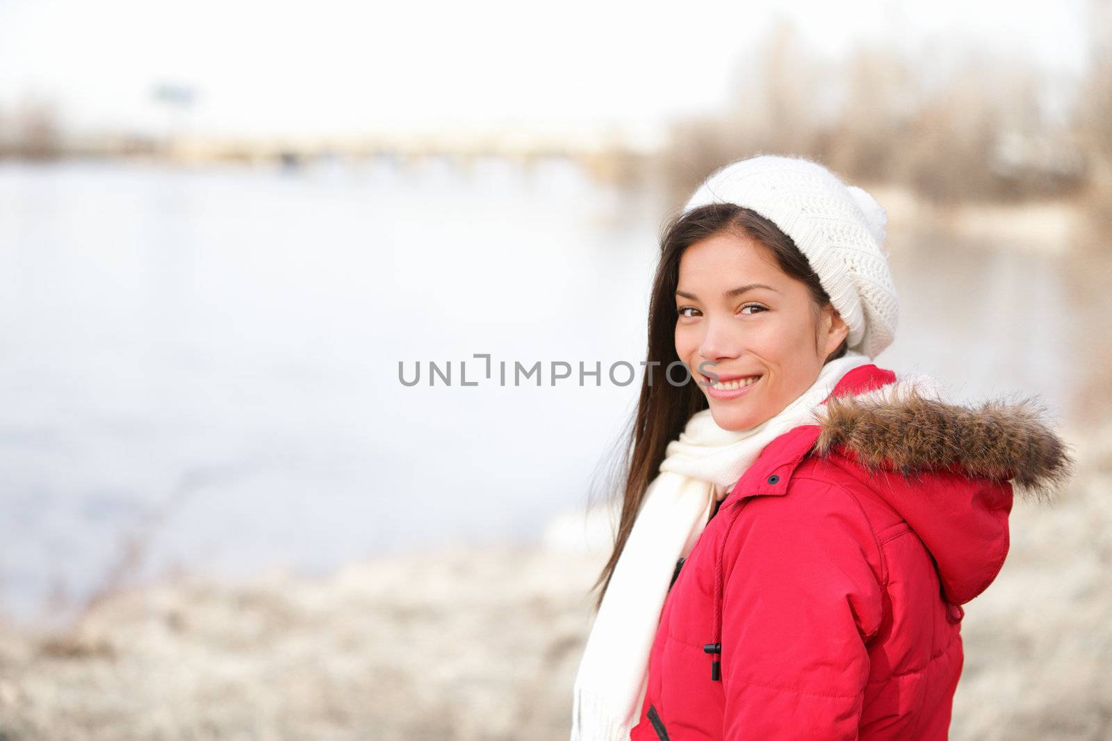 Winter woman portrait outside. Mixed-race girl smiling happy in cold winter landscape wearing warm winter clothing smiling happy looking at camera. Asian Chinese and Caucasian ethnicity. From Quebec, Canada.