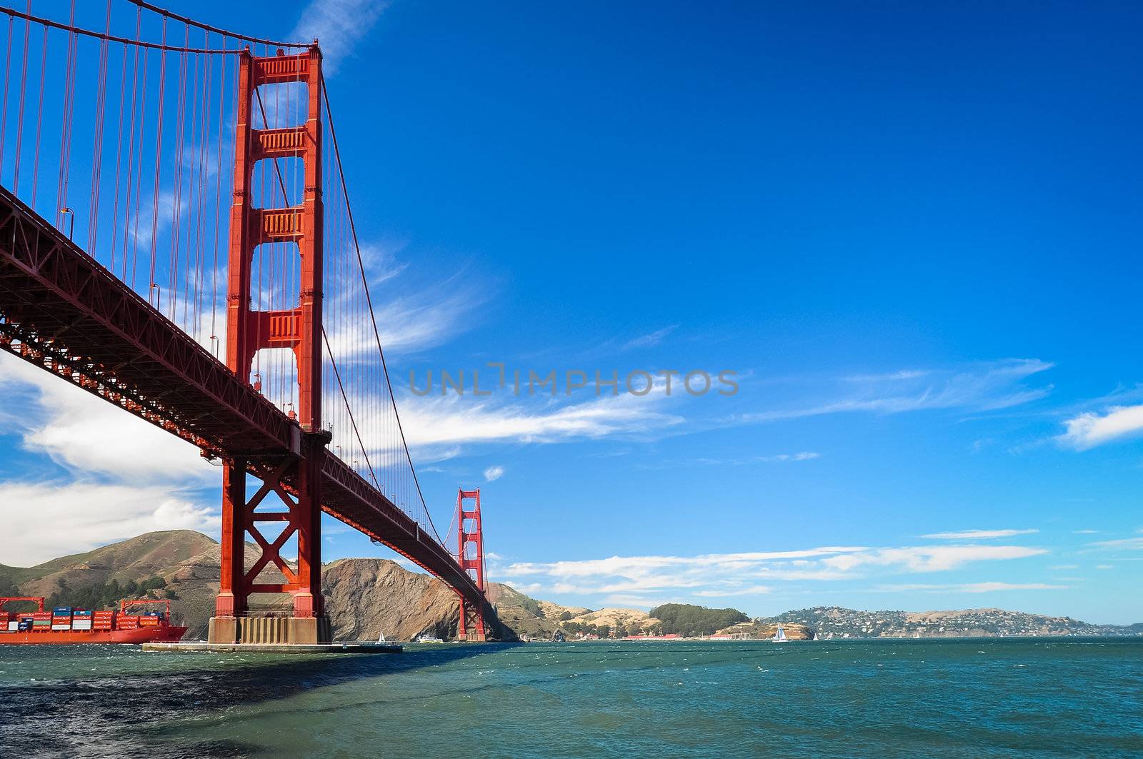 Golden Gate bridge detail with blue sky and white clouds and cargo boat