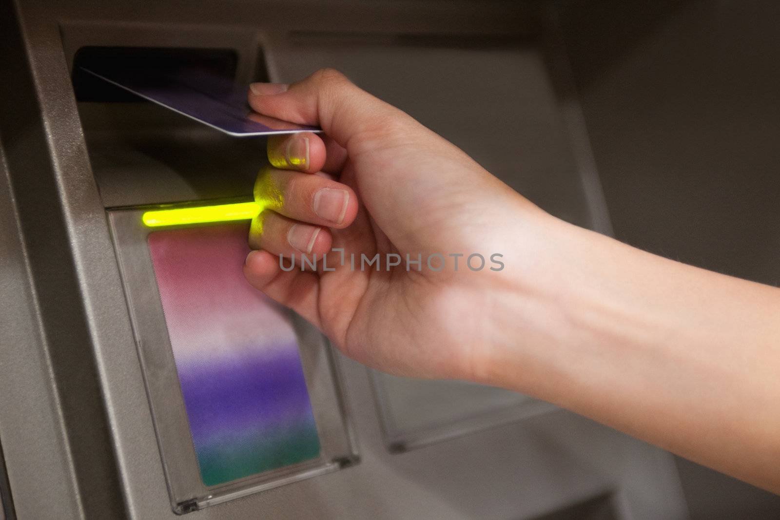 Close up of a hand inserting a credit card in an ATM
