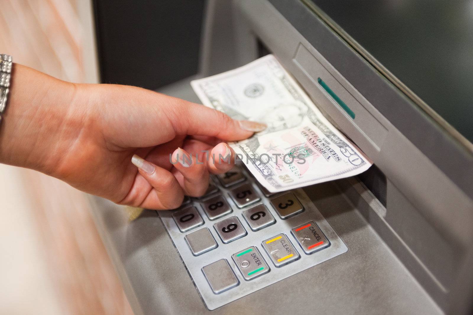 Feminine hand withdrawing dollars at an ATM