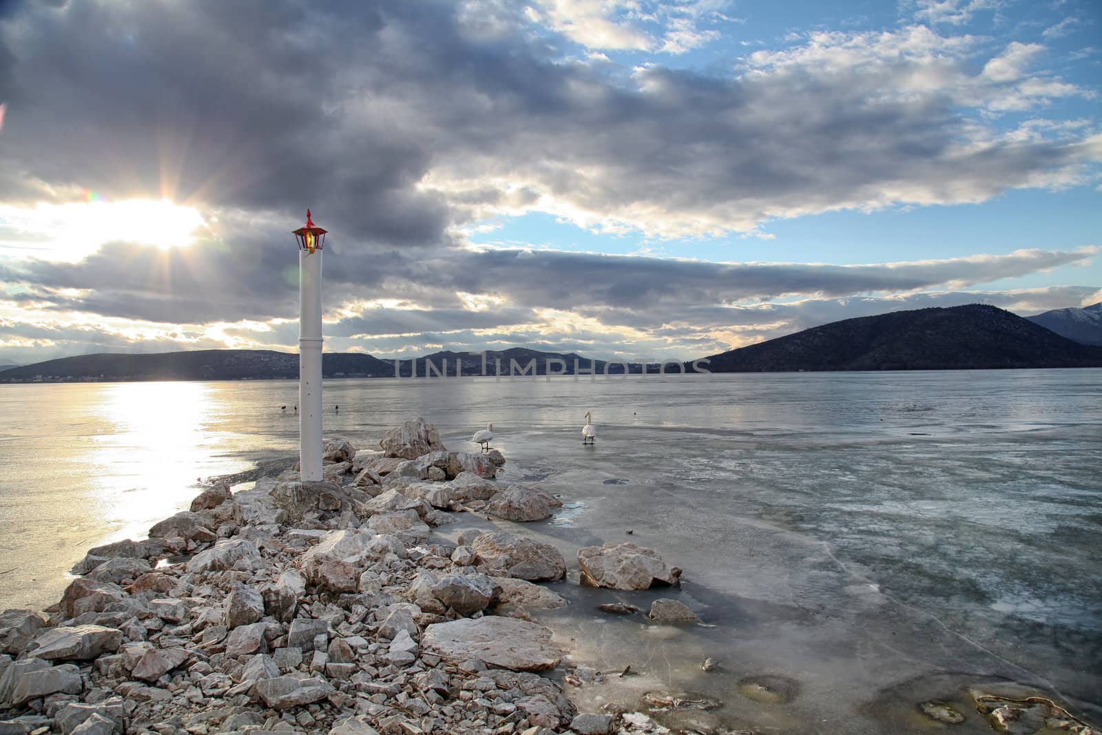 lighthouse in frozen lake by smixiotis_dimitrios