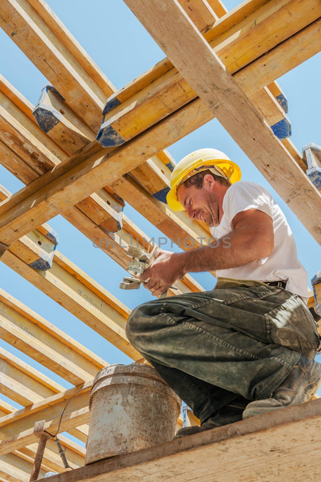 Smiling construction worker busy under slab formwork beams by akarelias