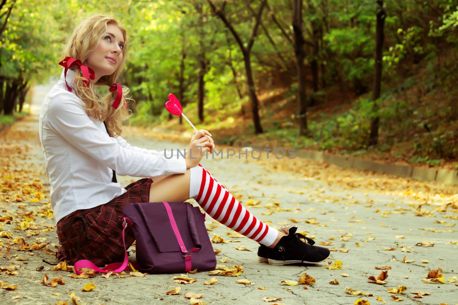 Dreaming schoolgirl sitting in autumn park