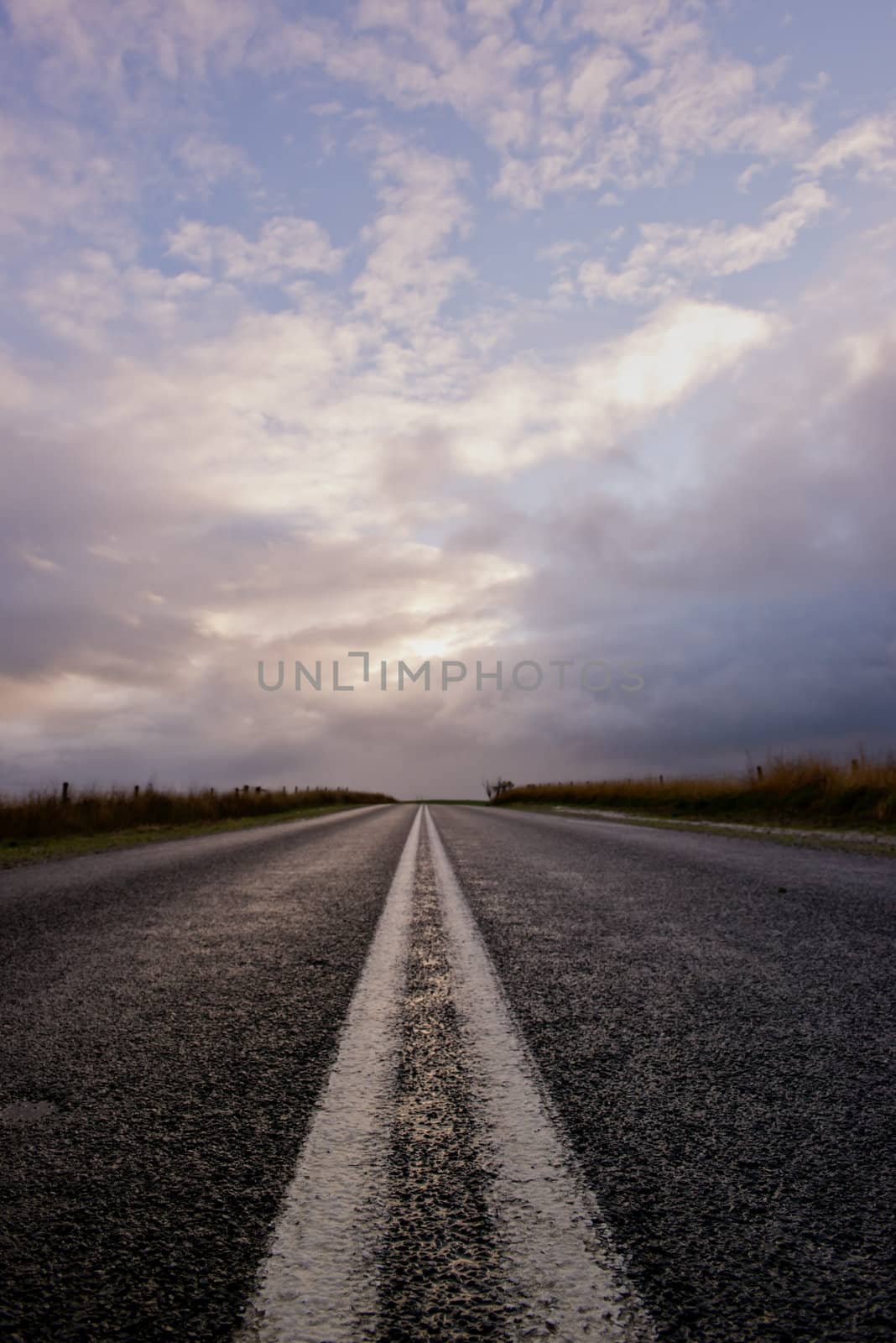 Journey on a country road with white lines leading to the horizon with a beautiful sky