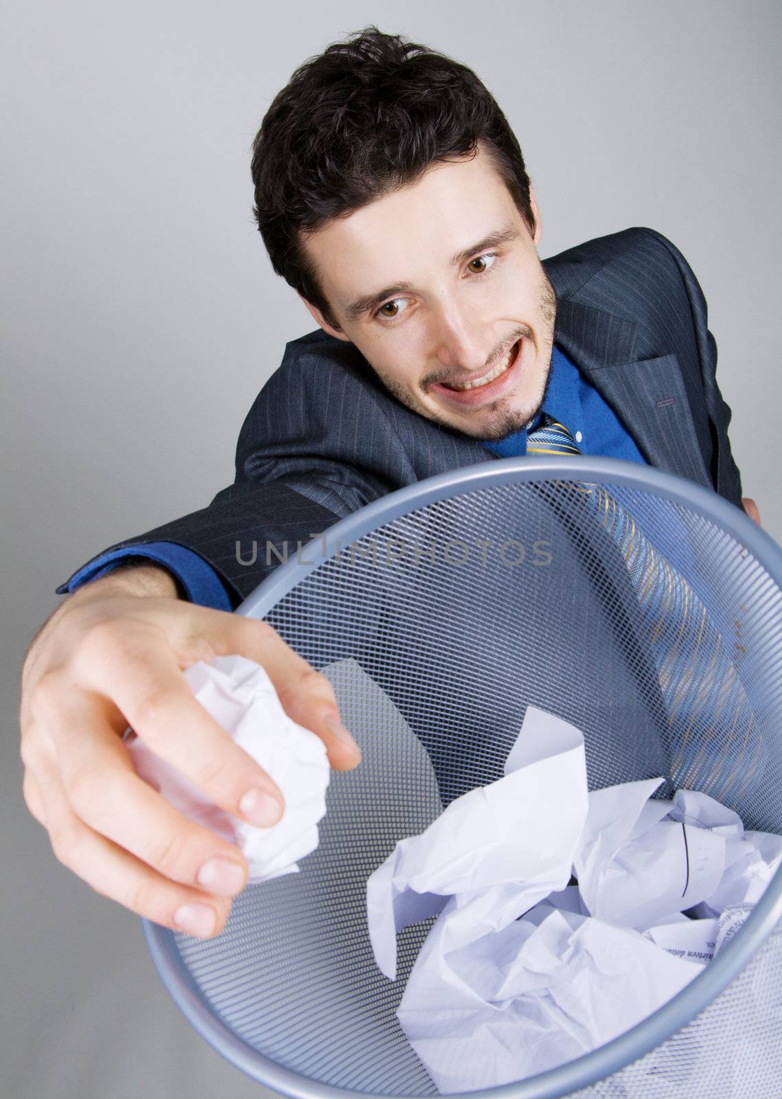 Young businessman playing baskteball with crumpled paper