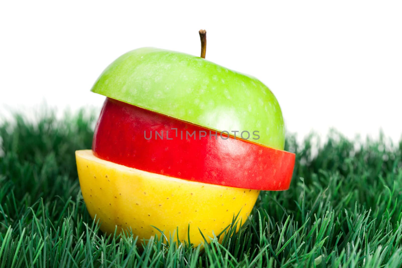 Combination of green, yellow and red apples on grass on a white background