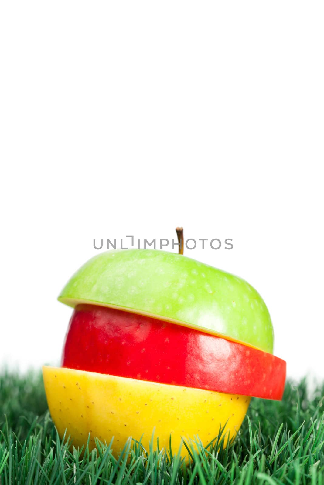 Combination of green, yellow and red apples on grass on a white background