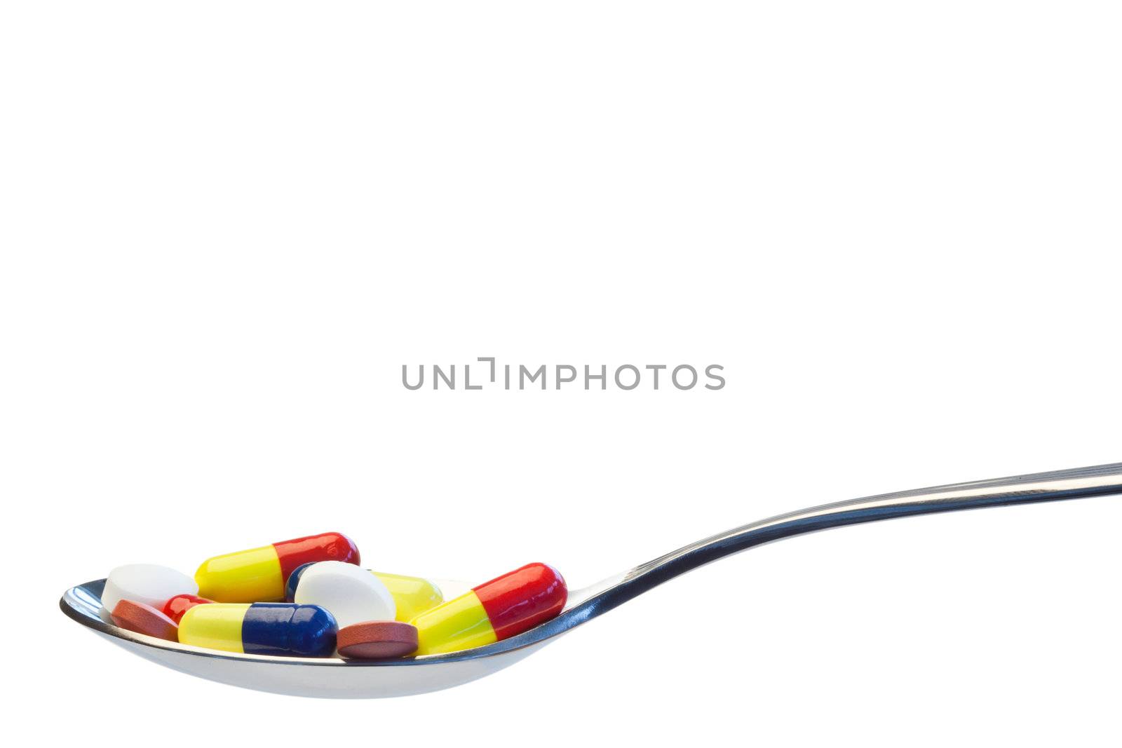 Spoon full of pills on a white background