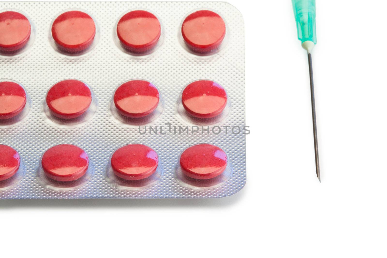 Blister strip of red pills and syringe on a white background