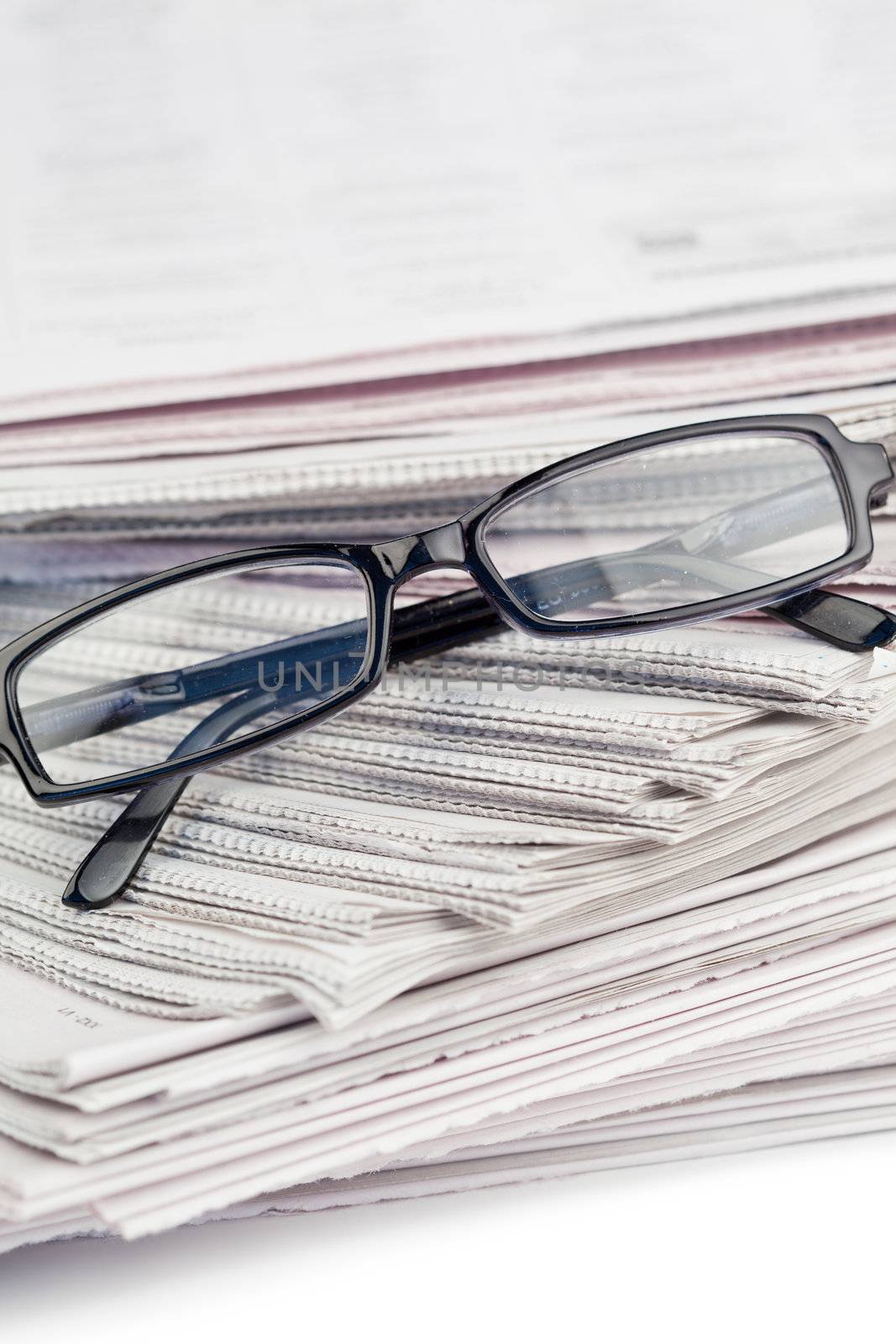 Newspapers and black glasses on a white a background