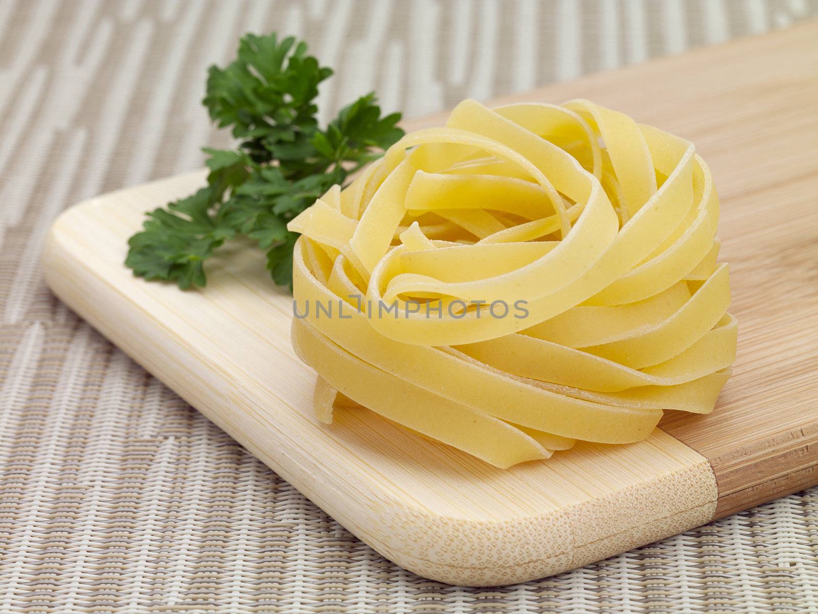 A nest of dry tagliatelle pasta on a cutting board