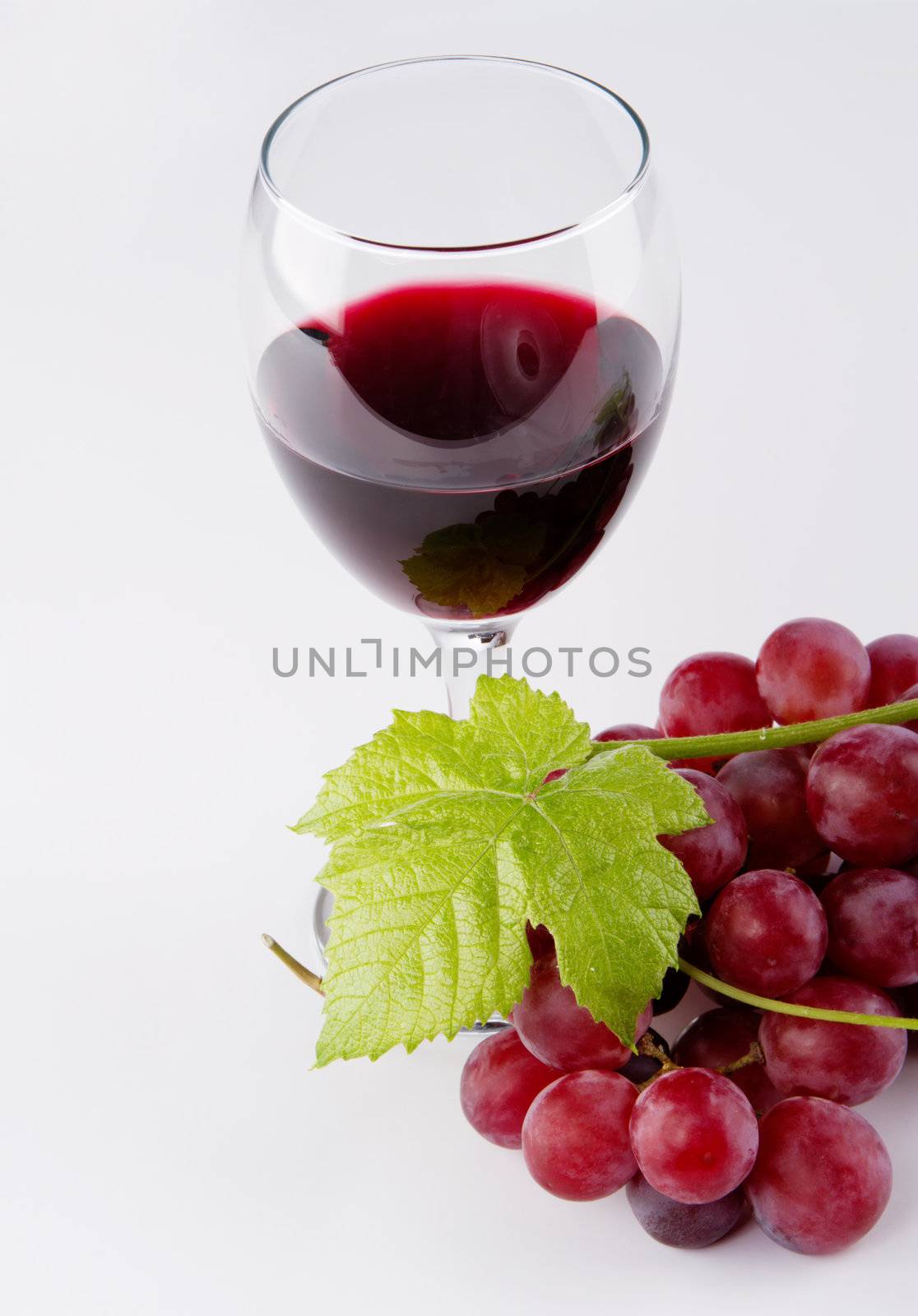 Glass of red wine with grapes on foreground