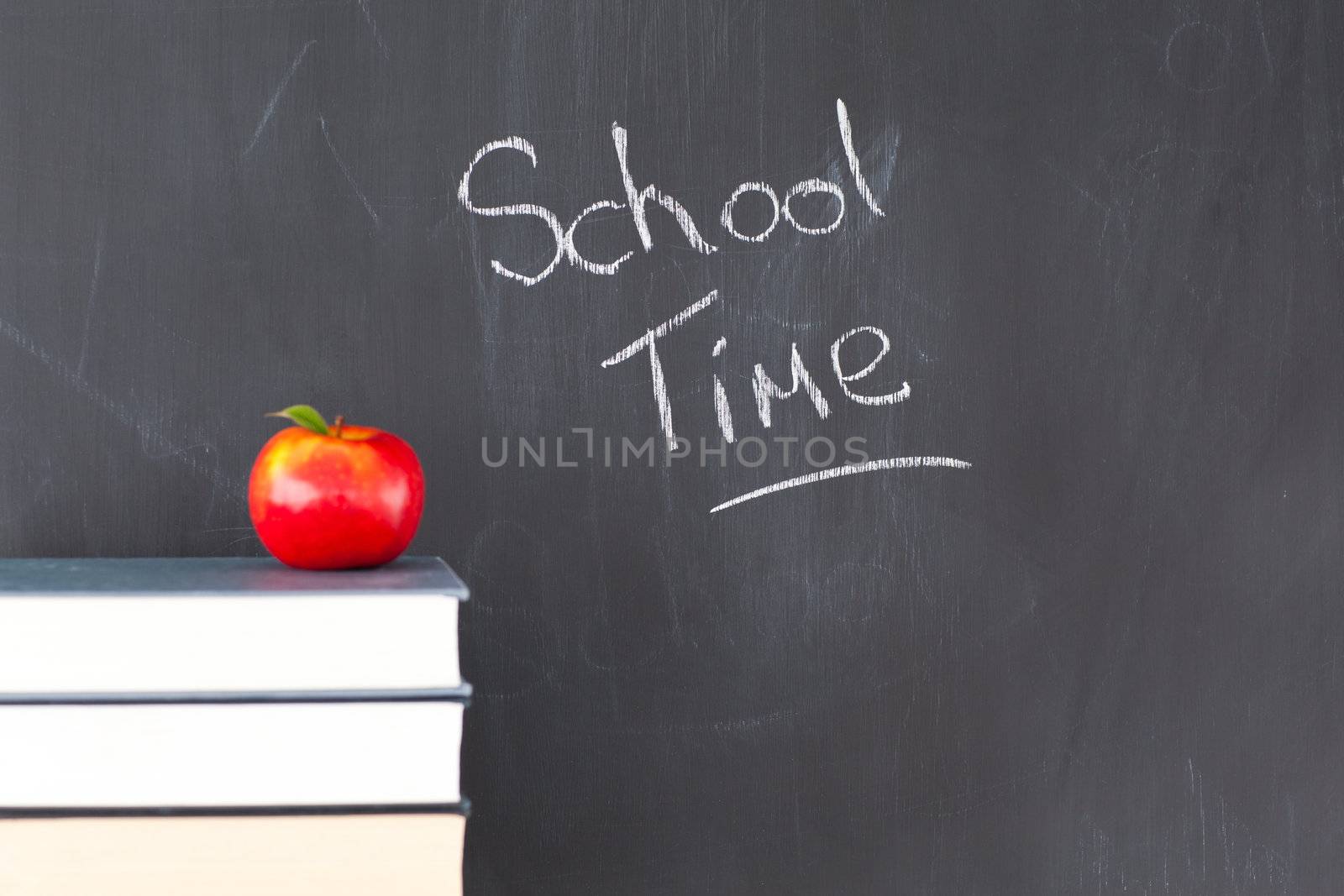 Stack of books with a red apple and a blackboard with "school time" written on it