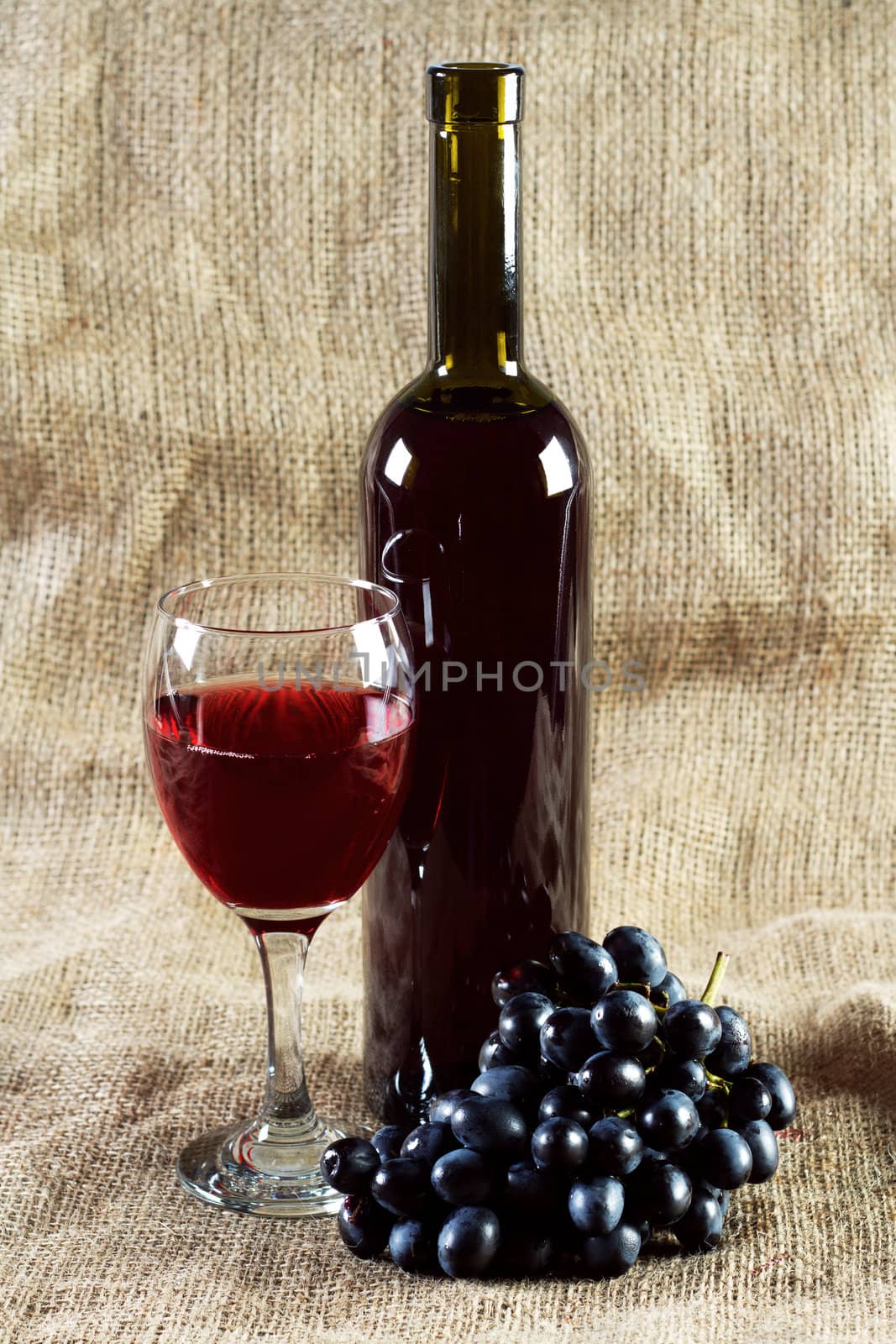 Red wine and grapes on vintage background by Gdolgikh