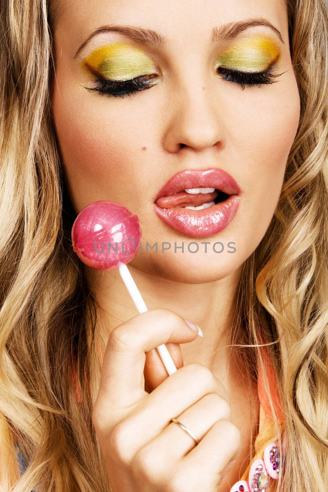 Beutiful woman with creative makeup holding a candy, closeup portrait