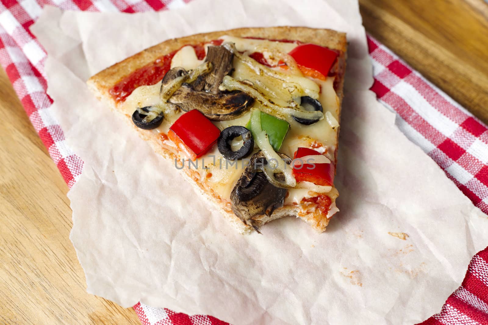 Macro shot of slice of pizza on tissue paper and napkin.