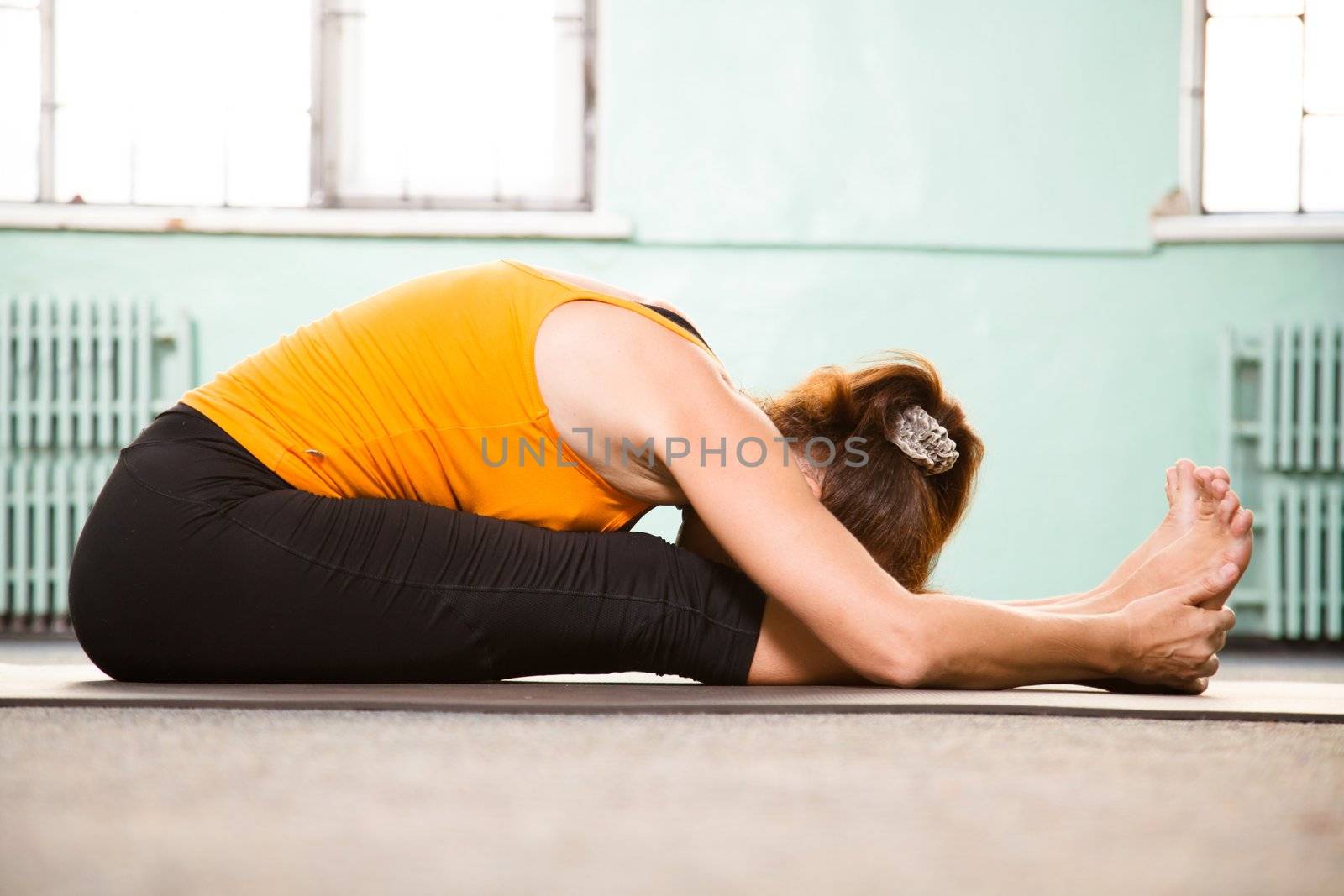 Mature woman exercising yoga in a gym