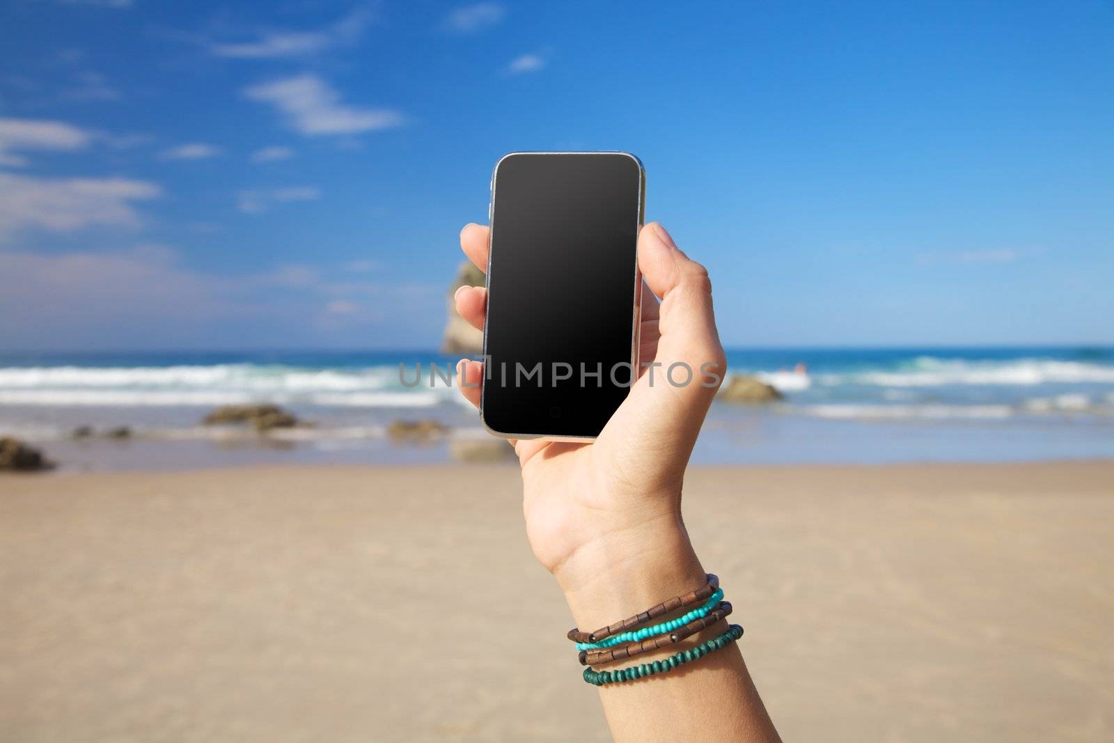 smart phone in woman hand on a beach in Asturias Spain
