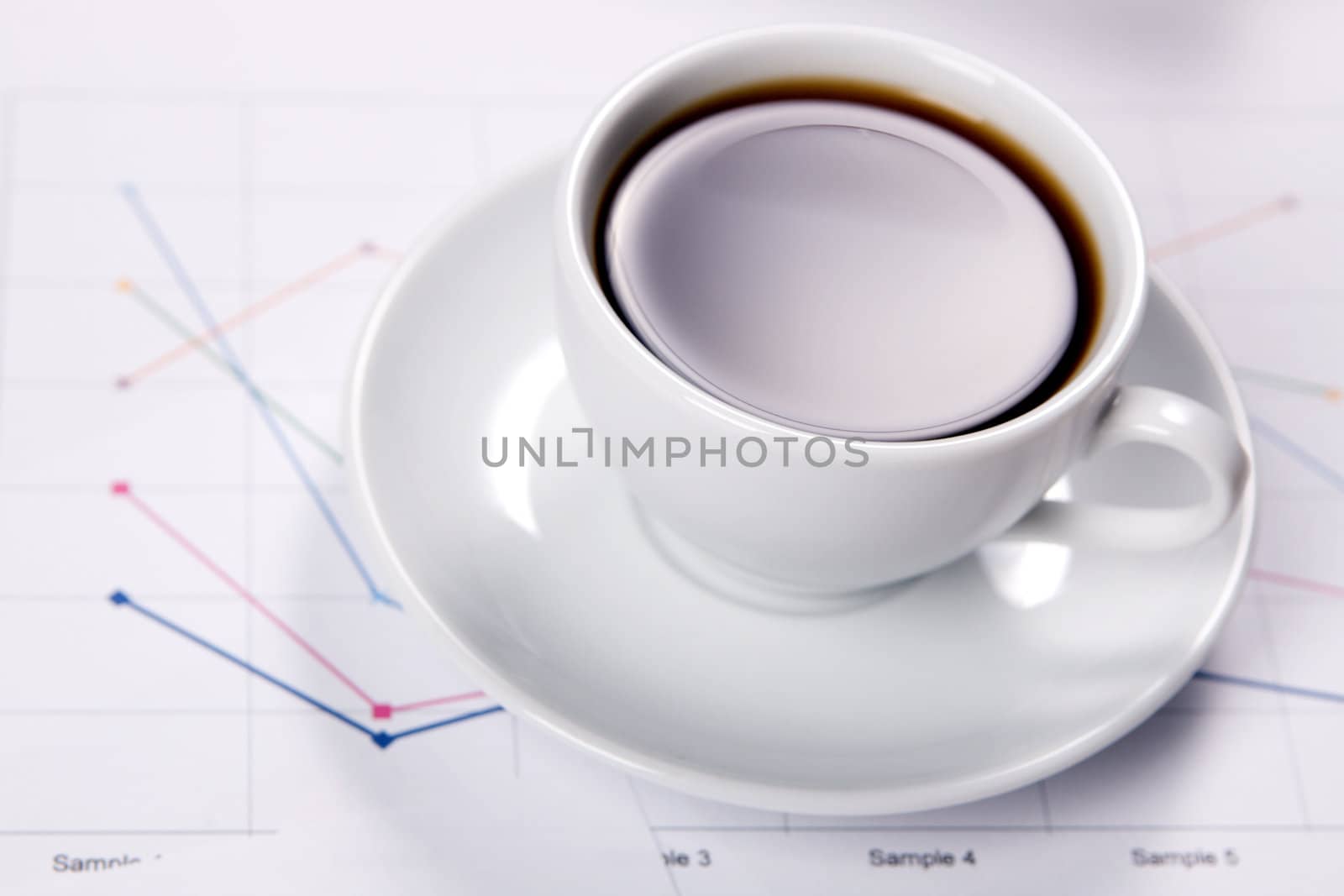 Cup of strong coffee over business diagrams by Gdolgikh