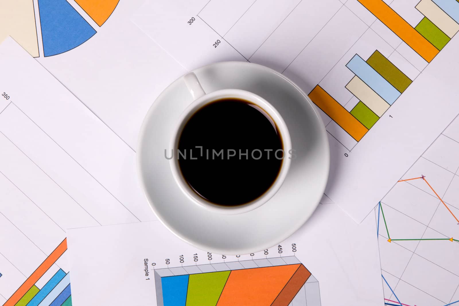 Cup of coffee over financial graphs, view from above