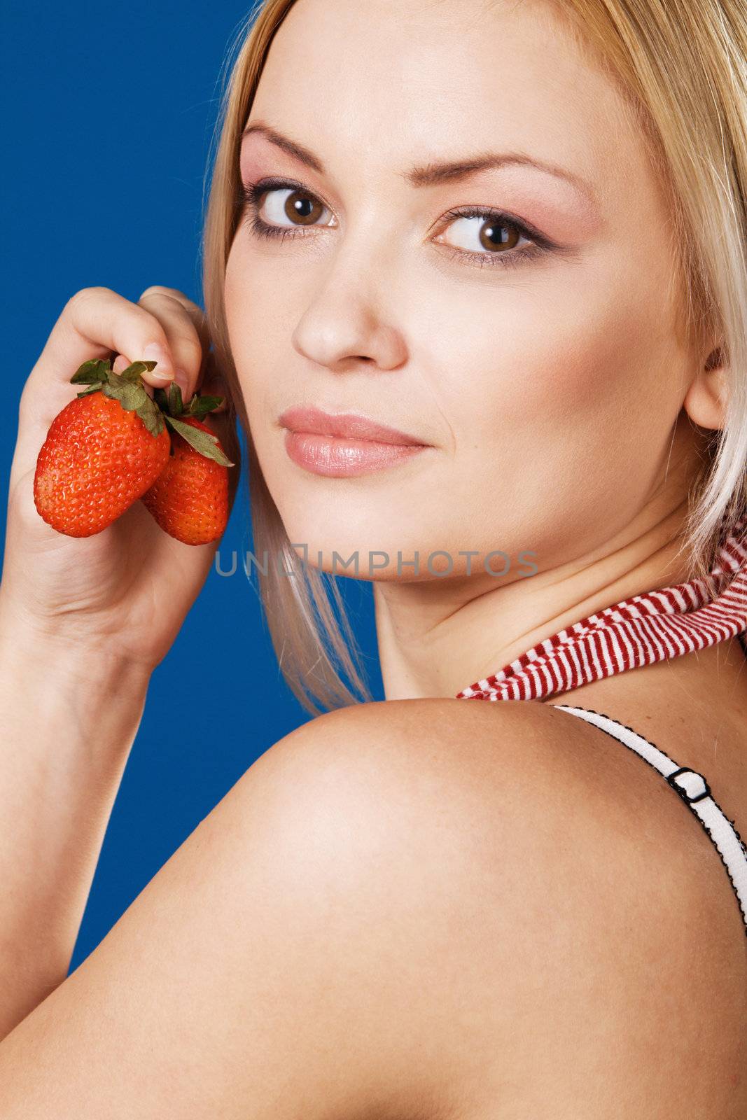 Beautiful girl tasting a strawberry, face portrait