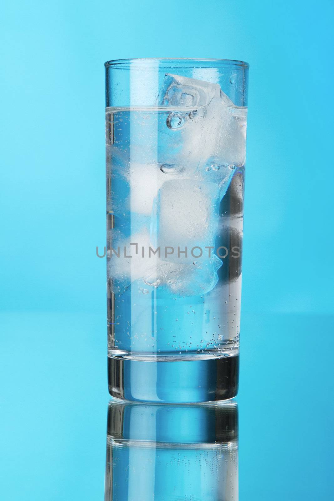 Glass of ice water on blue background by Gdolgikh