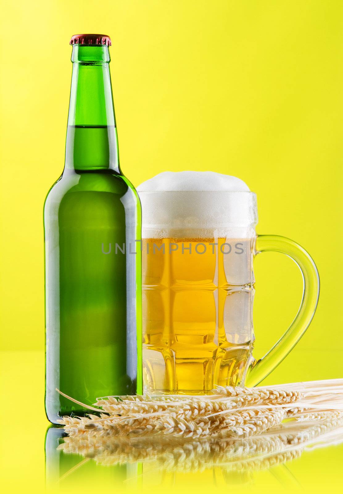 Beer mug and bottle on yellow background, studio photo