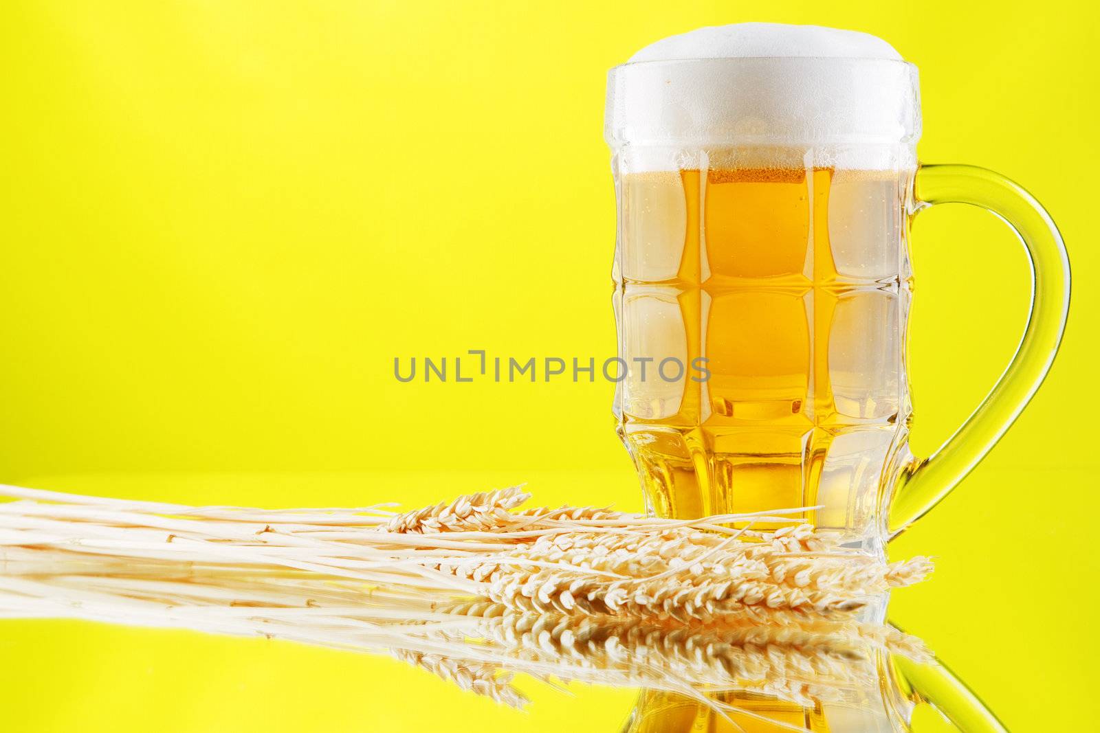 Beer mug and bottles on yellow background, studio photo