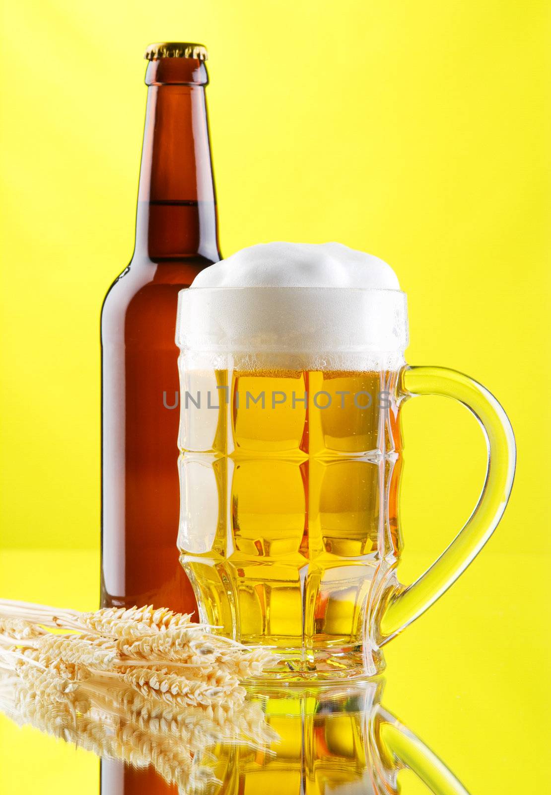 Beer mug and bottles on yellow background, studio photo
