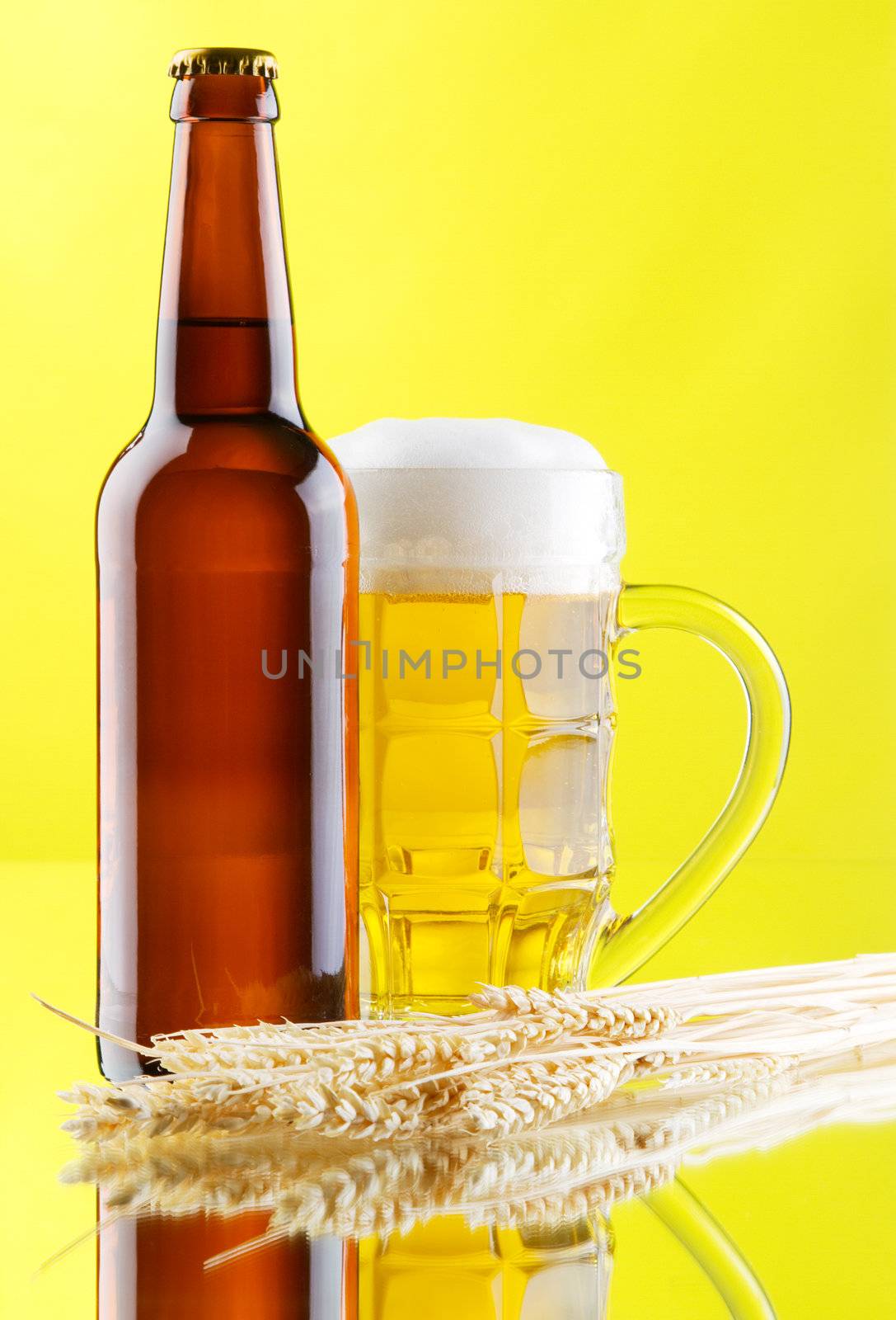 Beer mug and bottles on yellow background, studio photo