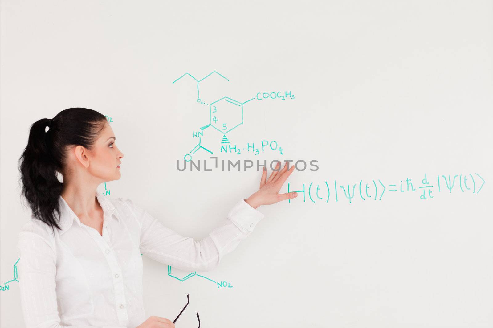 Scientist explaining a formula written on a white board to her students
