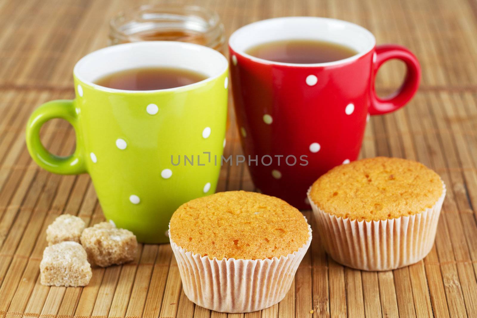 Two cups of sweet tea with sugar and cupcakes