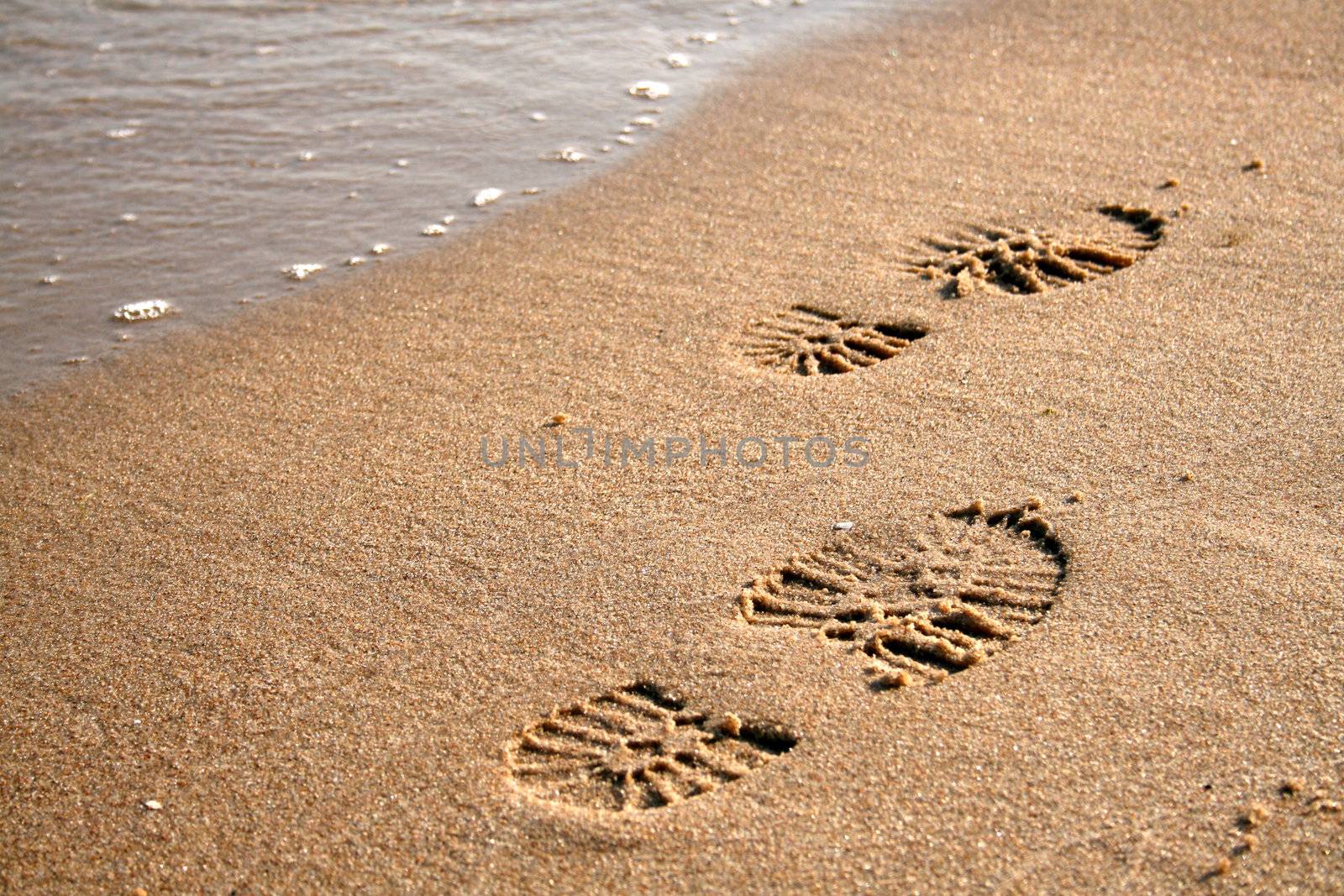 Footprints on the sand near the waves