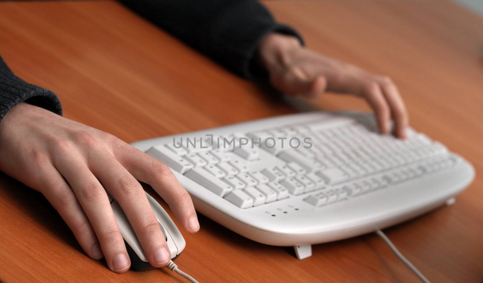 Man working with computer, with hands on mouse and keyboard, focus on the mouse