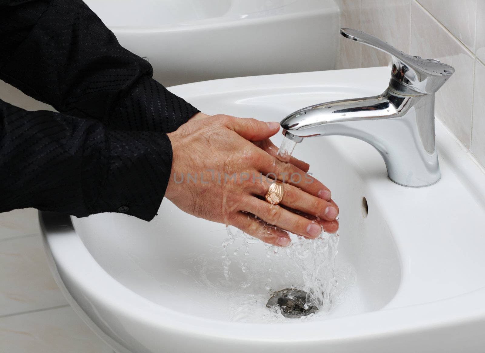 Man washing his hands under running water by Gdolgikh