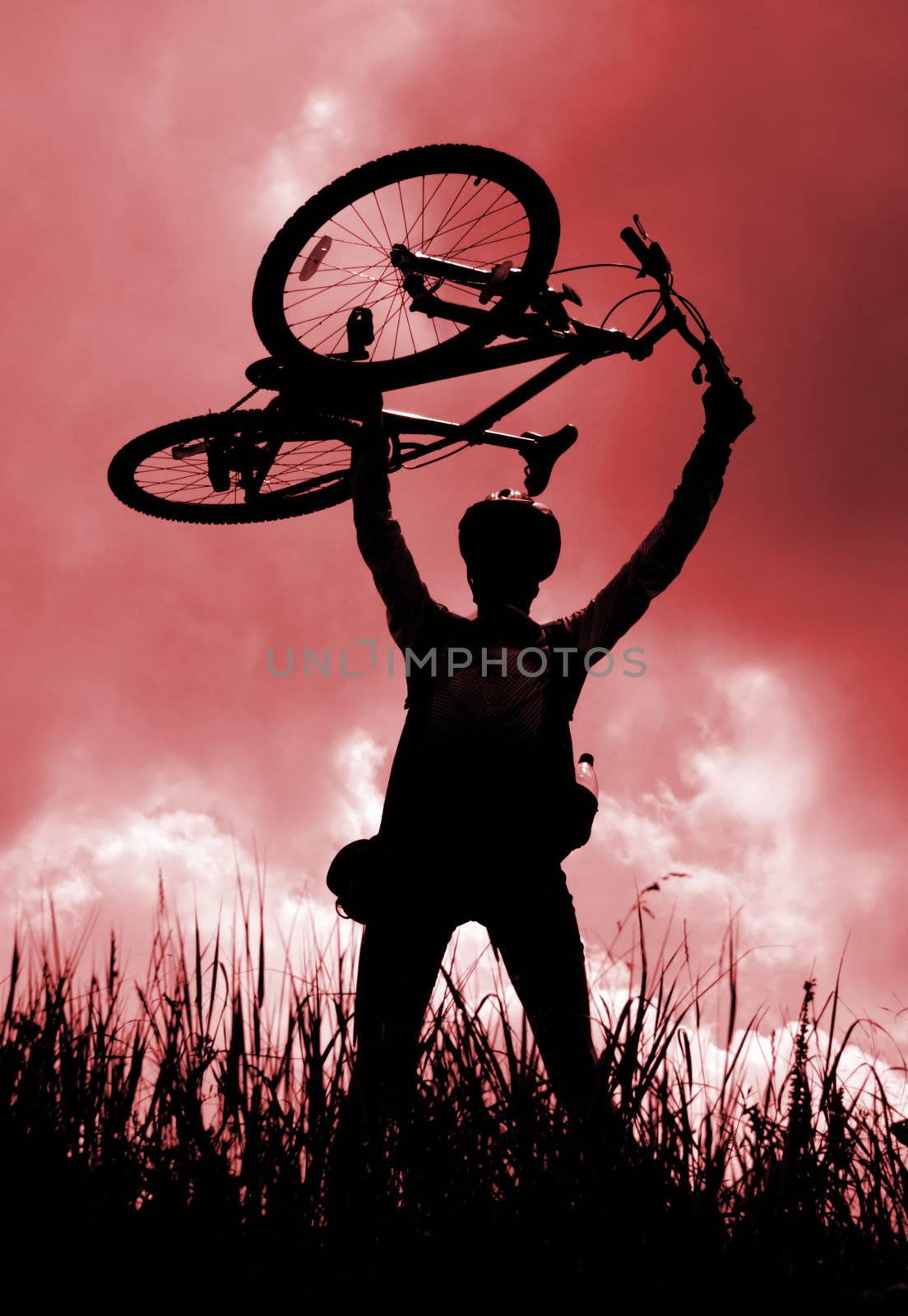 Silhouette of a biker holding his bicycle, red tint
