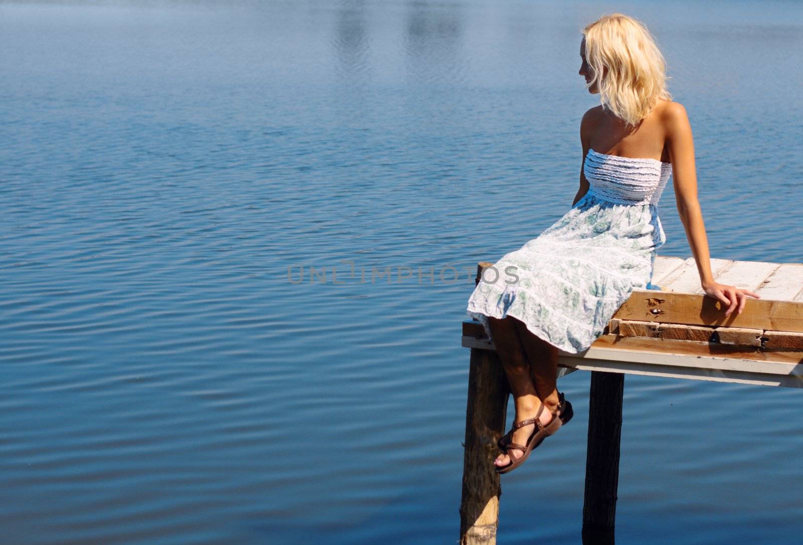 Girl sitting on a pier at the river bank, natural sun light