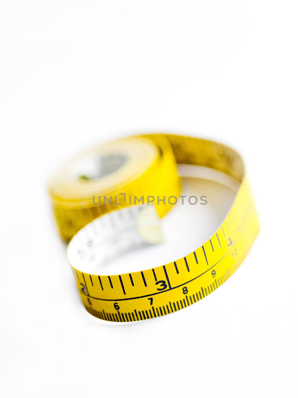 A mostly rolled up measuring tape on a white surface.