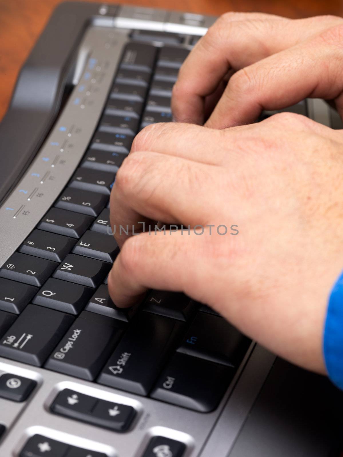 Close-up cropped image of human hands typing on black keyboard.