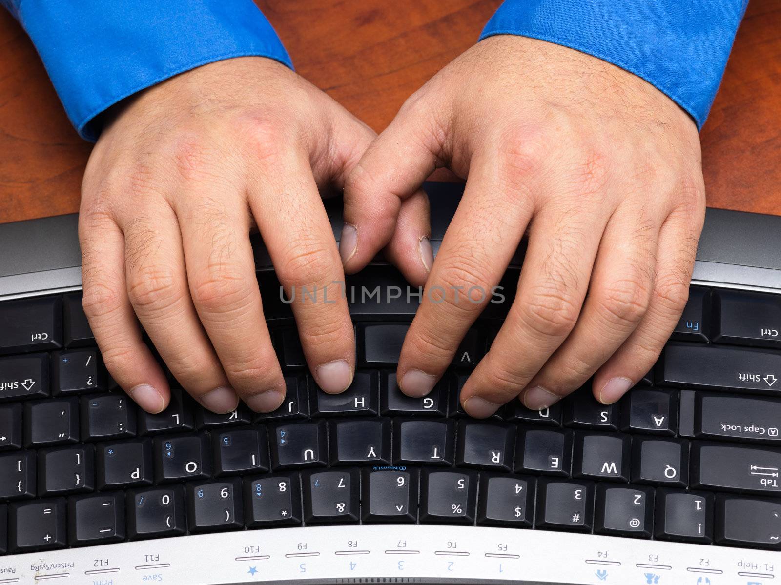 Close-up cropped shot of a human hands typing on black keyboard.