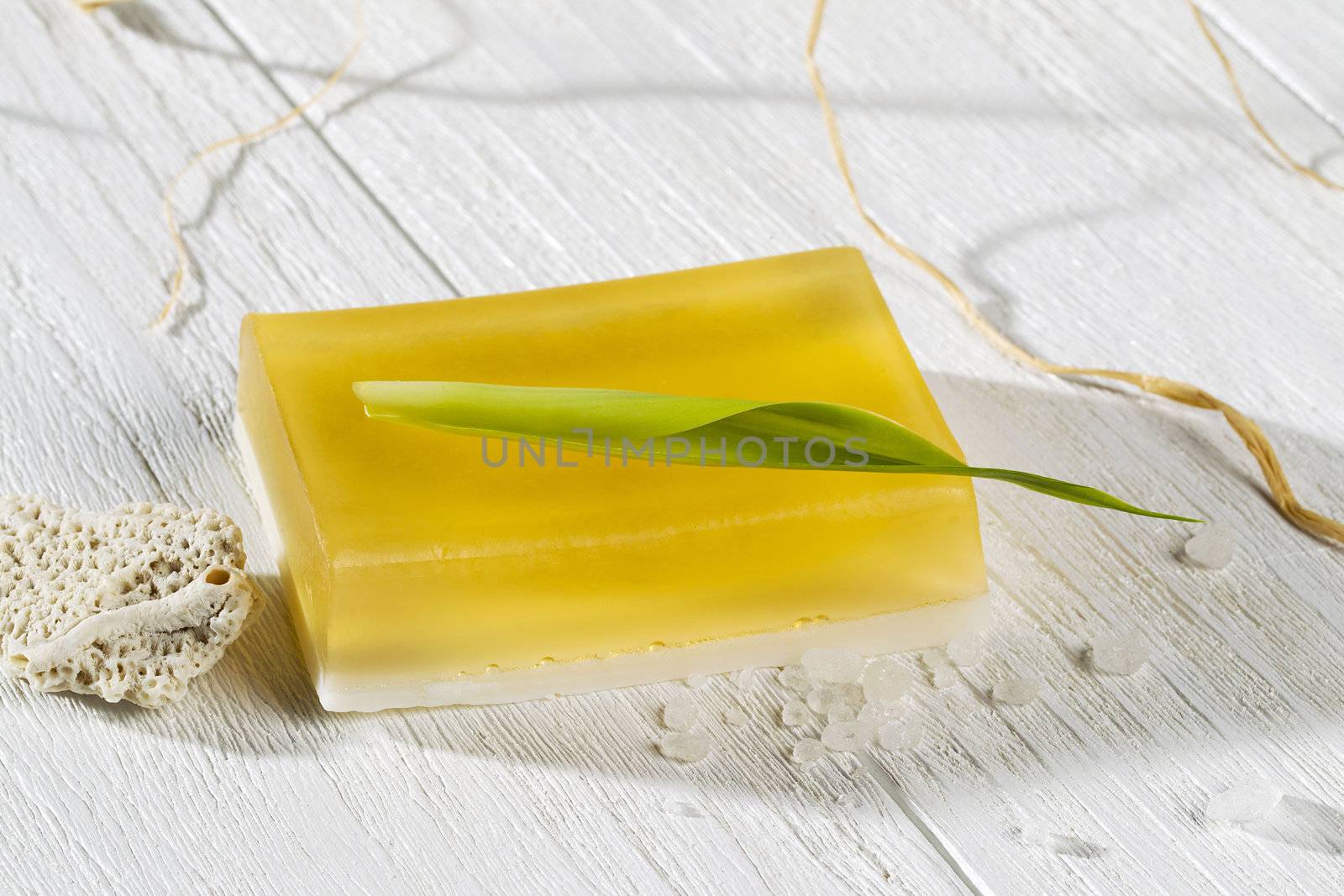 A close-up shot of a yellow bar soap on a white wooden background
